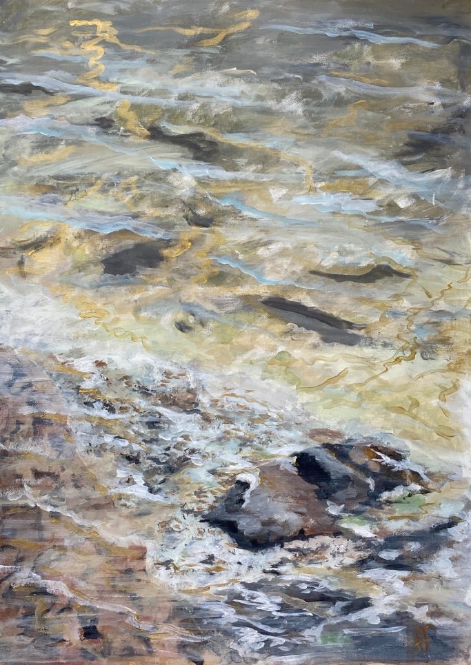 En strand med klippor och grunda vatten, reflektioner av ljus på ytan.