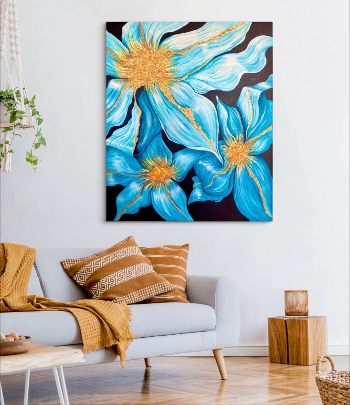 Färgglad tavla med blå blommor på en vit vägg ovanför en ljus soffa och kuddar.